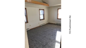 an empty room with two windows and carpet