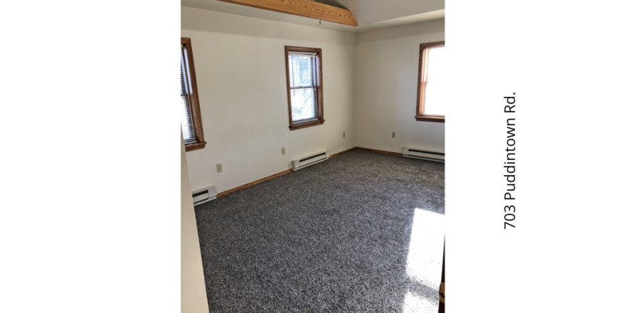 an empty room with two windows and carpet