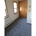 an empty room with carpet and two windows