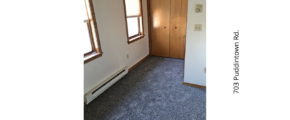 an empty room with carpet and two windows