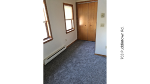 an empty room with carpet and two windows