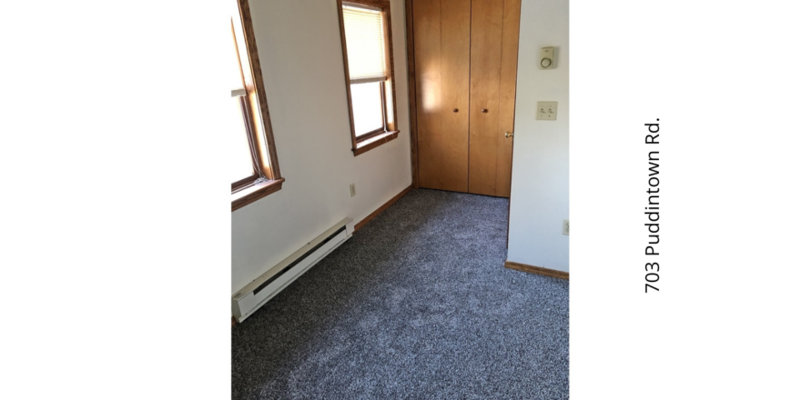 an empty room with carpet and two windows