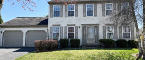 a two story house with white siding, gray shutters on windows, and a two car garage with gray doors