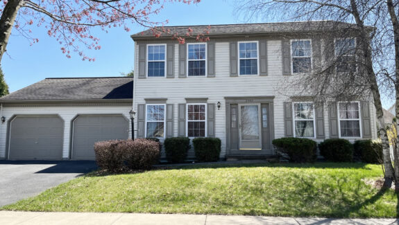 a two story house with white siding, gray shutters on windows, and a two car garage with gray doors