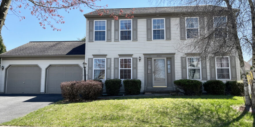 a two story house with white siding, gray shutters on windows, and a two car garage with gray doors