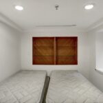 two beds in a small room with wooden shutters