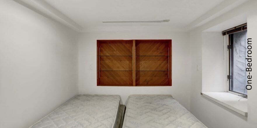 two beds in a small room with wooden shutters