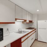 a kitchen with white cabinets and brown flooring