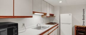 a kitchen with white cabinets and brown flooring
