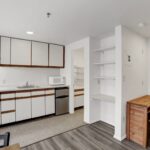 an empty kitchen with white cabinets and wood flooring