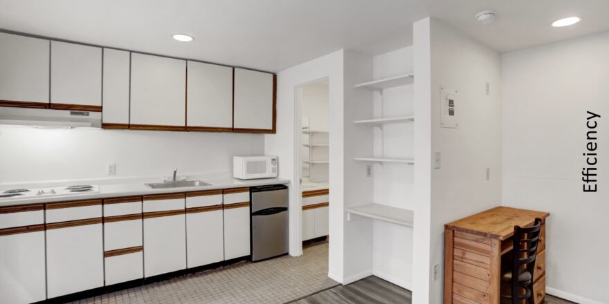 an empty kitchen with white cabinets and wood flooring