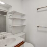 a bathroom with a toilet, sink and shelves