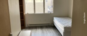 an empty bedroom with a bed and window