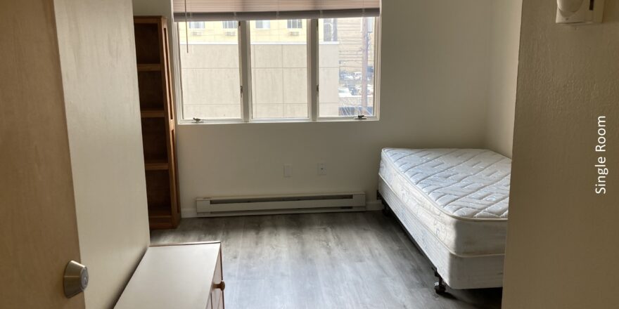 an empty bedroom with a bed and window