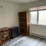 a room with a desk, bookcase and television