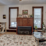 downstairs unit living room filled with 3 windows, white walls, and wooden flooring