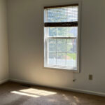 an empty room with a window and blinds