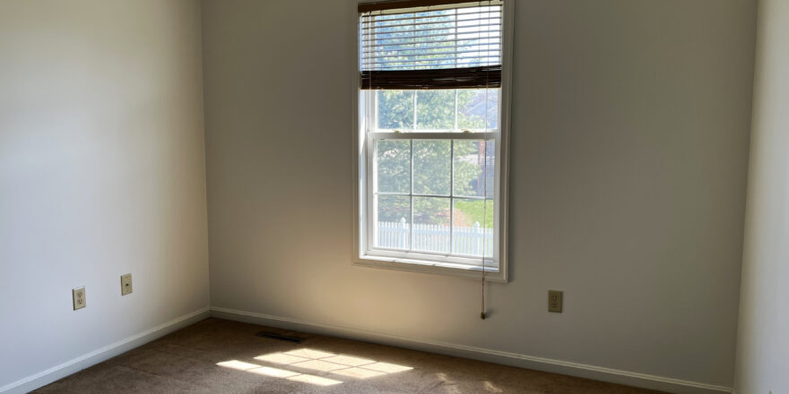 an empty room with a window and blinds