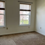 a empty bedroom with two windows