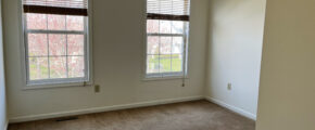 a empty bedroom with two windows