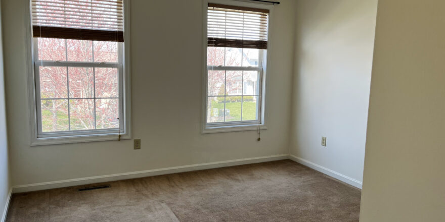 a empty bedroom with two windows