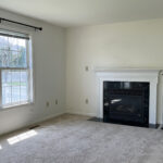 an empty living room with a fireplace and large windows