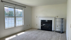 an empty living room with a fireplace and large windows
