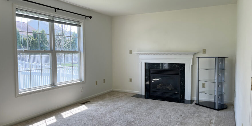 an empty living room with a fireplace and large windows