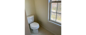 a white toilet sitting next to a window in a bathroom