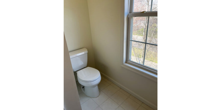 a white toilet sitting next to a window in a bathroom