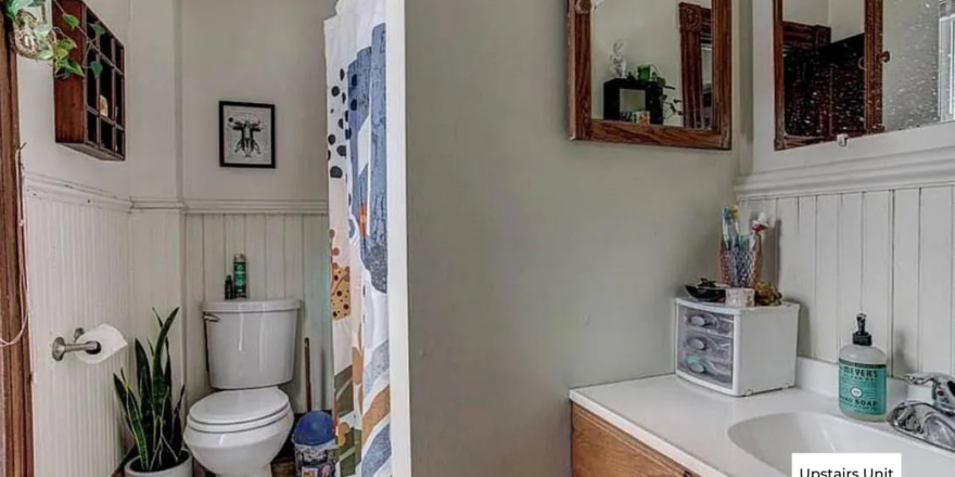 upstairs unit bathroom with a toilet, sink and mirror