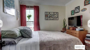 upstairs unit 1st bedroom with a neatly made bed and white walls