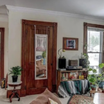 upstairs unit living room with white walls, a window in the corner, and light carpeting