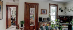 upstairs unit living room with white walls, a window in the corner, and light carpeting