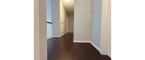 an empty hallway with hard wood floors and white walls