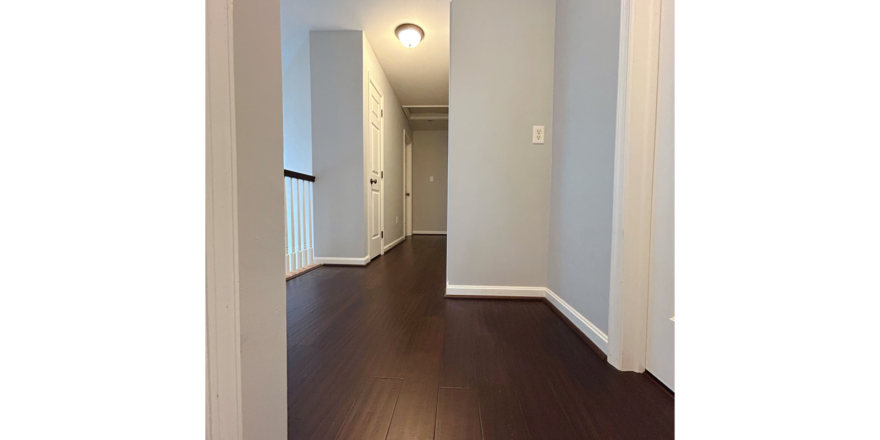 an empty hallway with hard wood floors and white walls