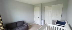 a carpeted bedroom with a couch, crib, and a closet