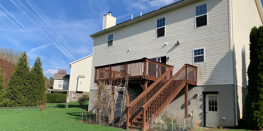 back exterior of house with a wooden staircase leading up to the deck