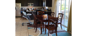 a dining room table and chairs in a kitchen with appliances and back door