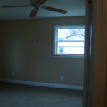 an empty room with a ceiling fan and window