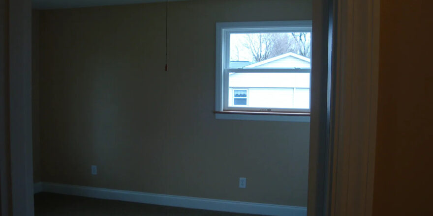 an empty room with a ceiling fan and window