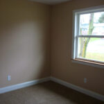 an empty room with a window and carpeted floor