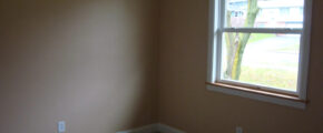 an empty room with a window and carpeted floor