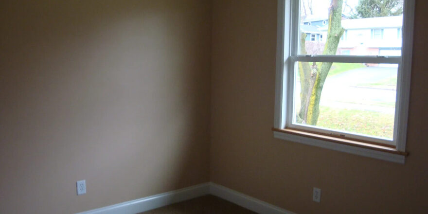 an empty room with a window and carpeted floor