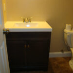 a bathroom with a toilet, sink and mirror