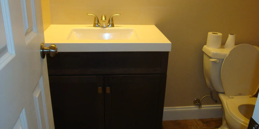 a bathroom with a toilet, sink and mirror