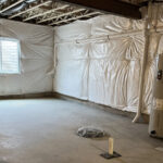 an unfinished basement with white tarps covering the walls