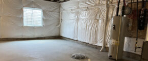 an unfinished basement with white tarps covering the walls