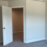 an empty room with two white doors open, one of which is a walk in closet