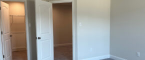 an empty room with two white doors open, one of which is a walk in closet